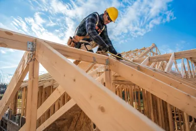 Timmerman meet een spant op tijdens het opbouwen van een dakconstructie