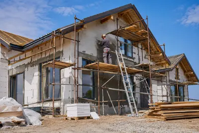 Vakman werkt de gevel af vanaf de steiger bij een nieuwbouwwoning