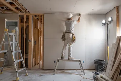 Vakman zet een gipsplaat tegen de wand bij een verbouwing